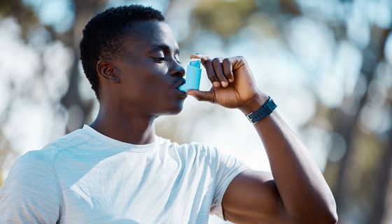 Junger Mann, nutzt ein Asthmaspray.