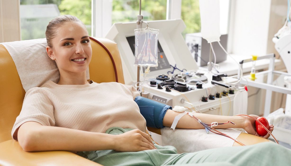 Junge Frau auf einer Liege beim Blutspenden.