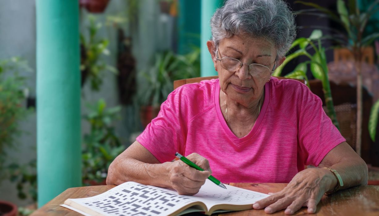 Ältere Frau, löst ein Kreuzworträtsel.