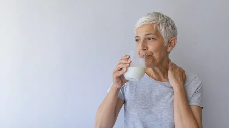 Ältere Frau, trinkt ein Glas Milch.