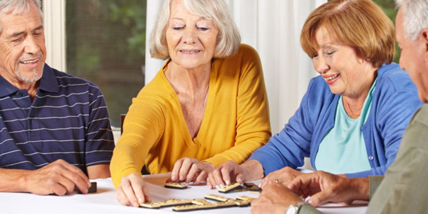 Aktive Senioren sitzen an einem Tisch und spielen ein Gesellschaftsspiel