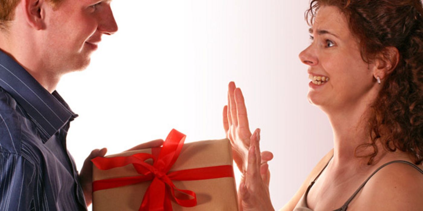 Mann überreicht ein Geschenk an seine Frau, die dankend ablehnt