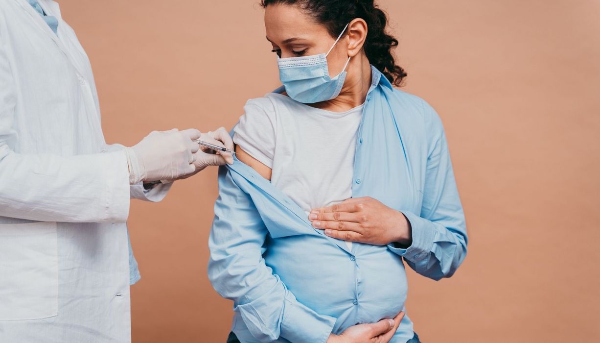 Schwangere Frau, bekommt eine Impfung vom Arzt.