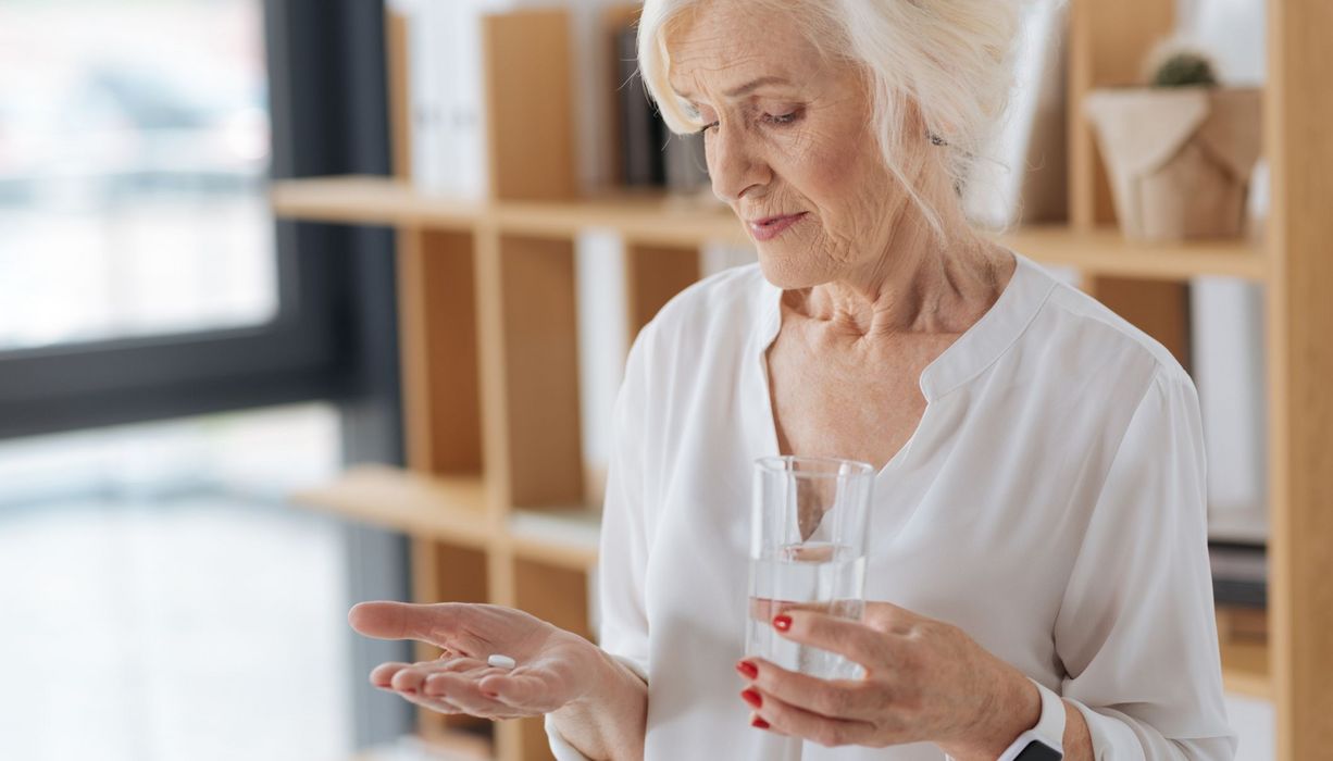 Ältere Frau, ca. 65 Jahre alt, nimmt eine Tablette.