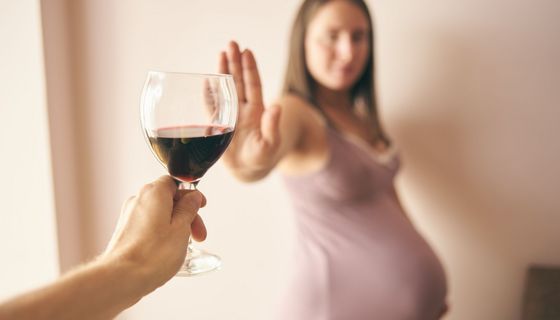 Schwangere Frau, lehnt ein Glas Wein ab.