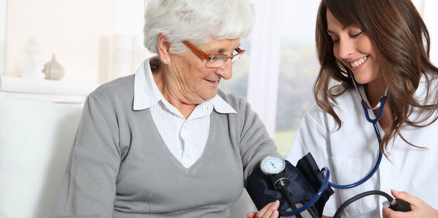 Junge Ärztin misst bei älterer Dame den Blutdruck