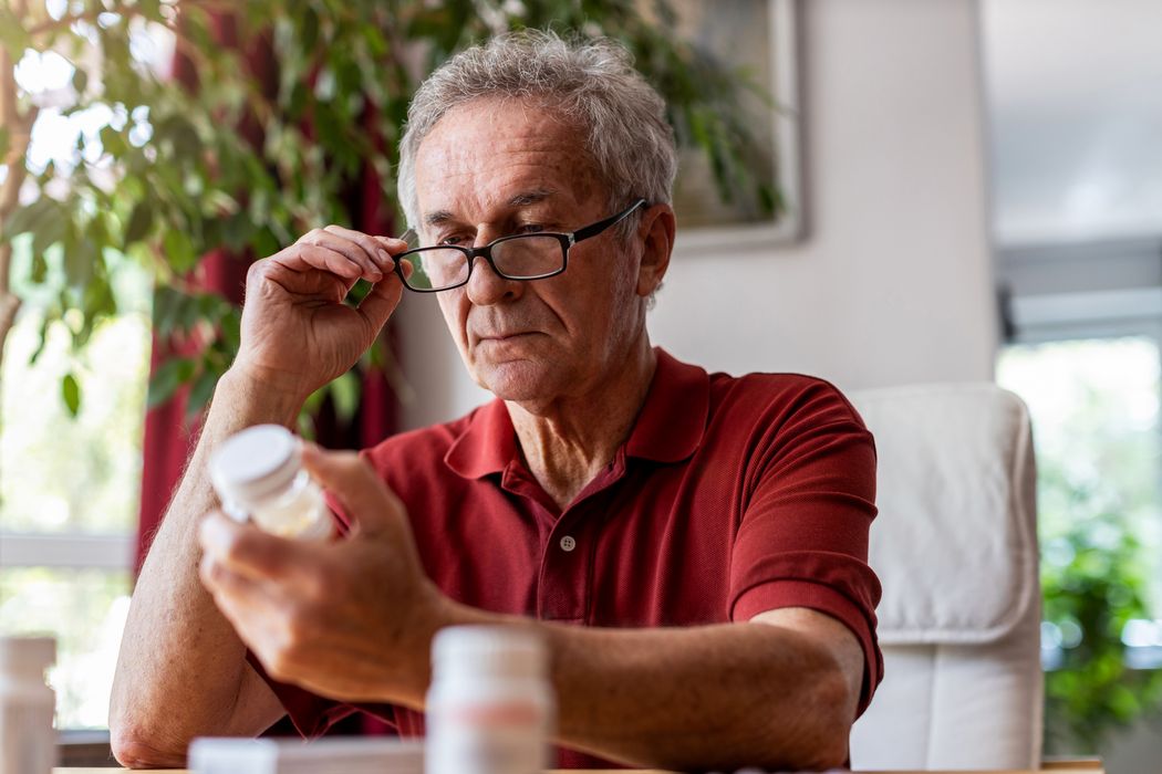 Älterer Mann schaut kritisch auf eine Medikamentenpackung.