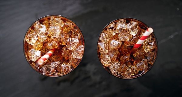 Zwei Gläser mit Cola und Eis auf dunklem Hintergrund.
