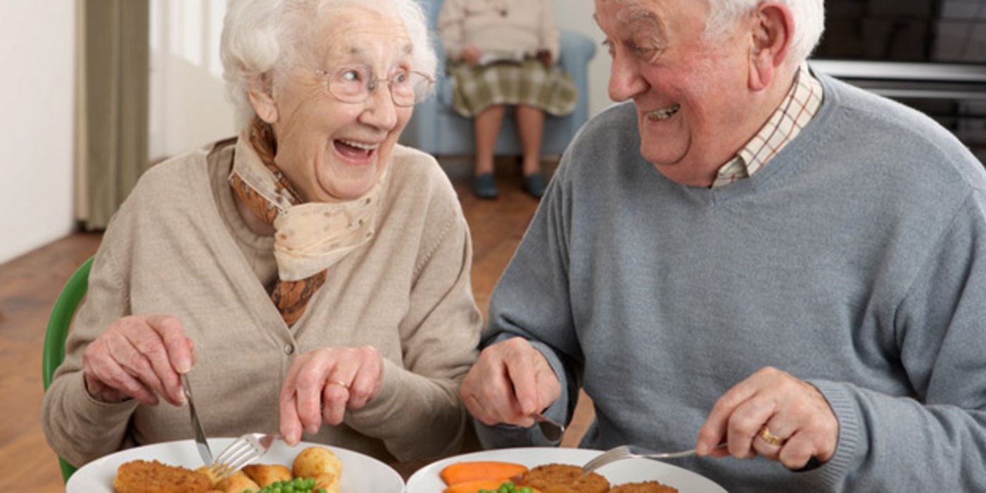 Seniorenpaar isst zu Mittag und strahlt sich an