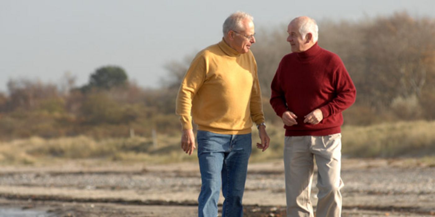 Zwei ältere Männer gehen am Strand spazieren.