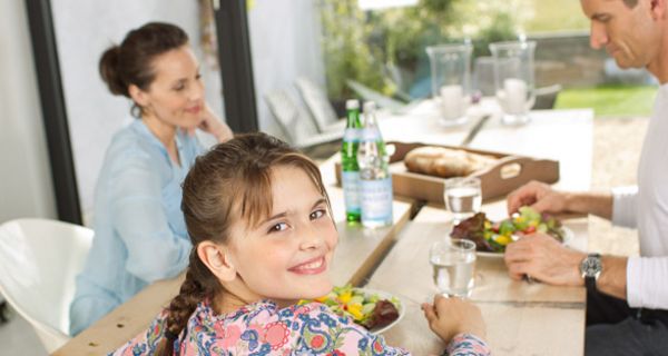 Tisch mit Wassergläsern und Familie beim Essen