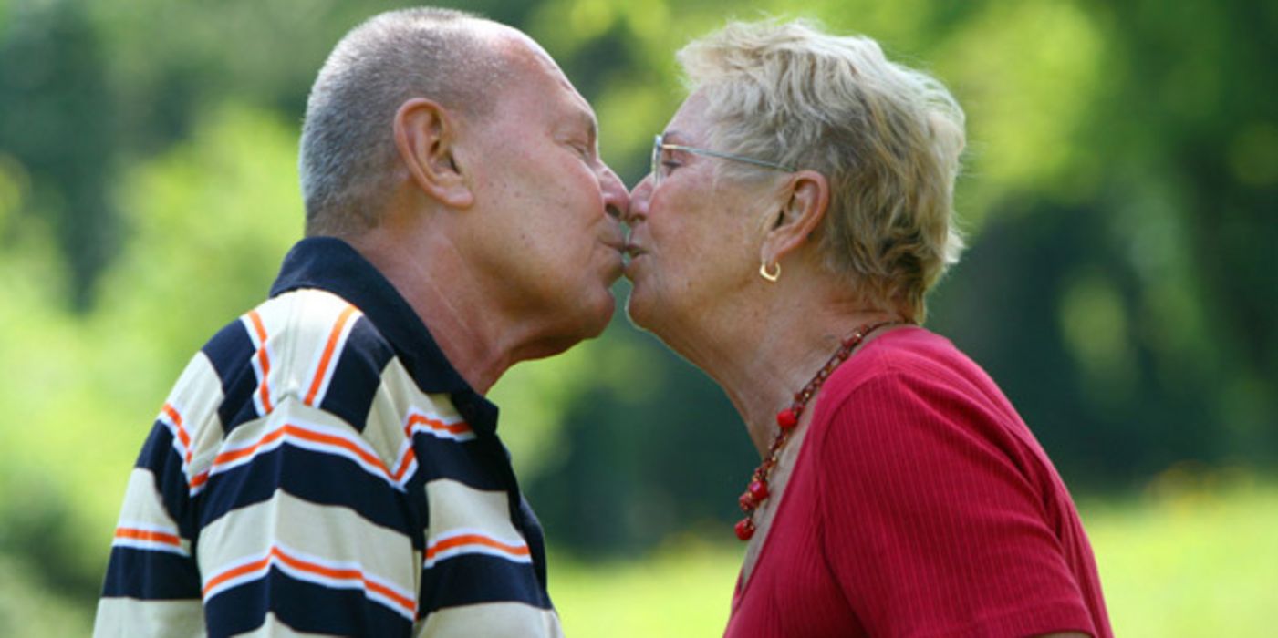 Alter Mann und alte Frau küssen sich.