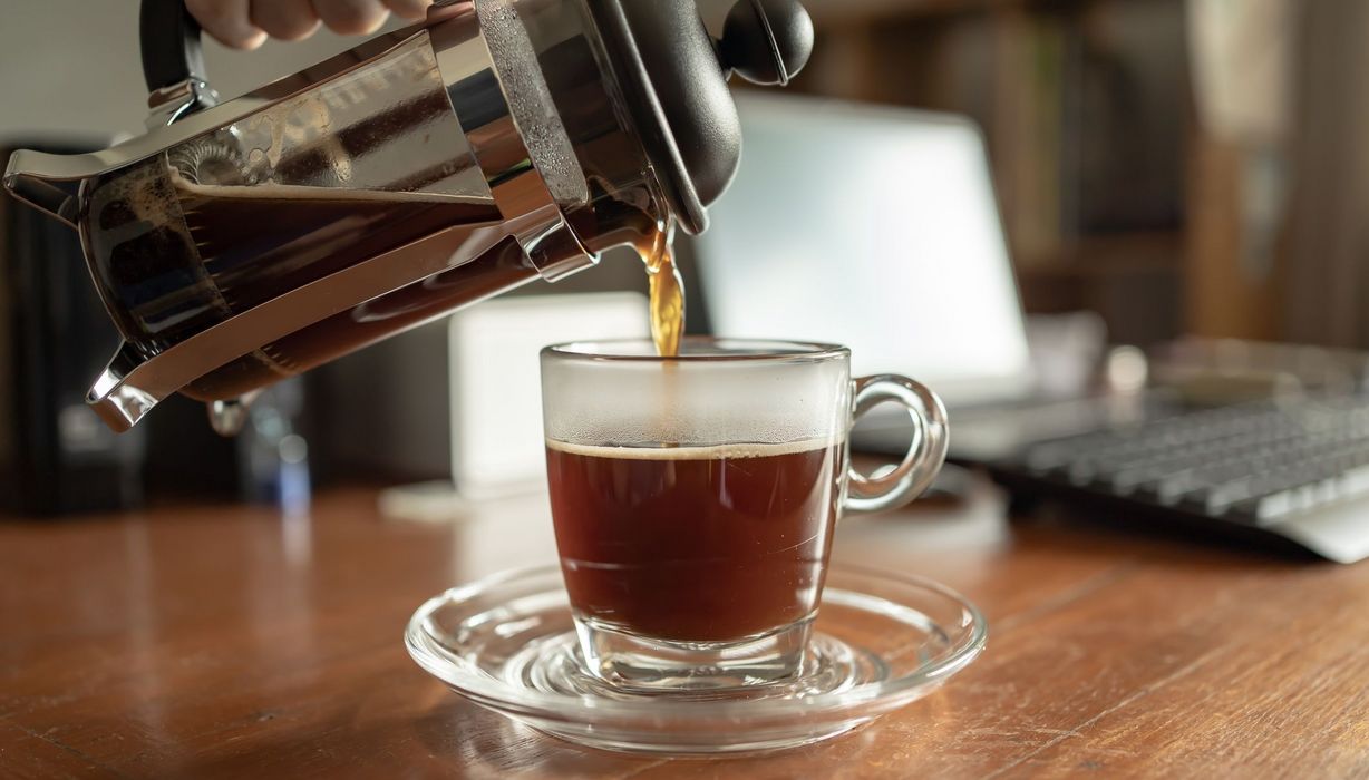 Kleiner Espresso, wird aus einer Kanne eingeschenkt in eine durchsichtige Tasse.