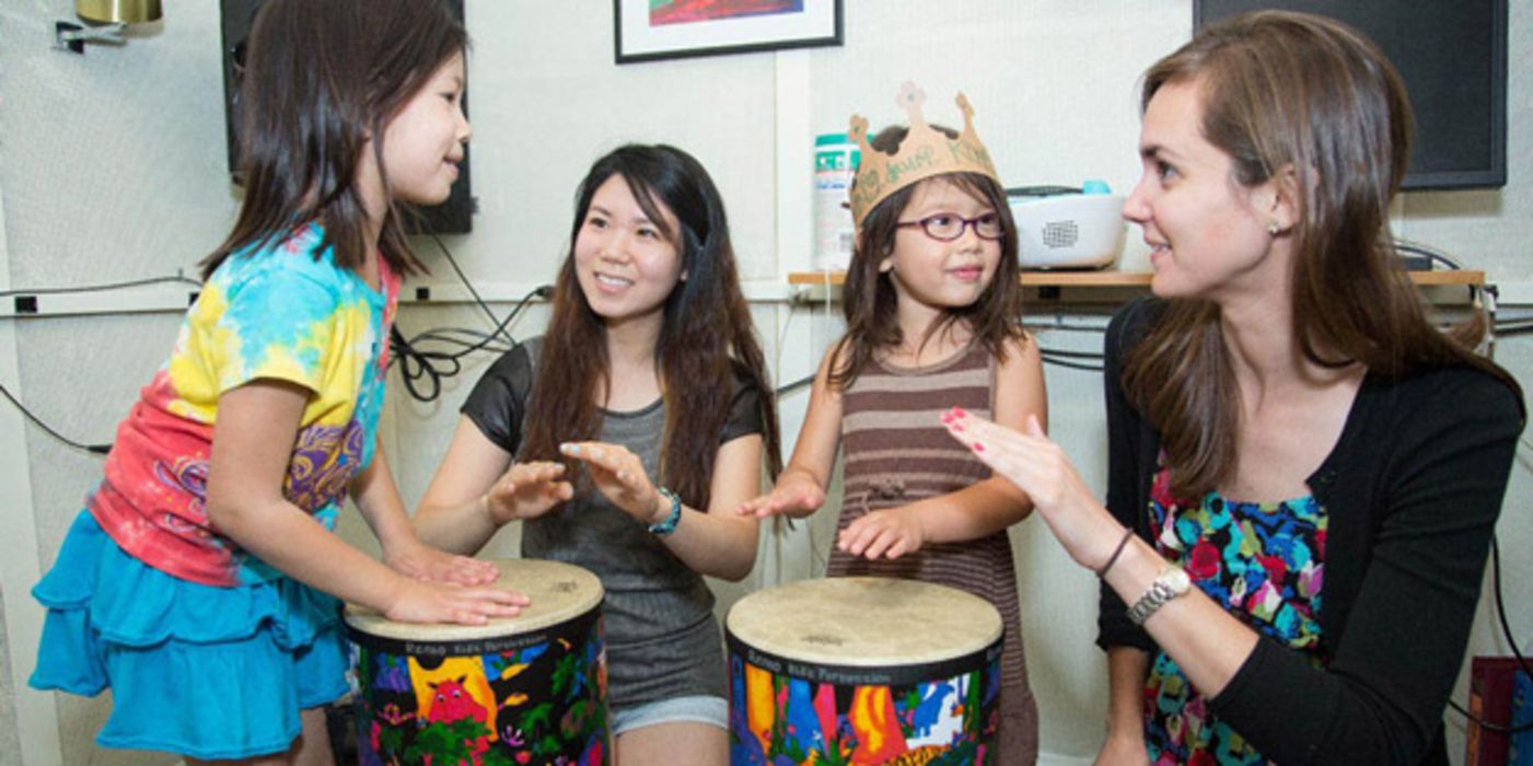 Lehrerin beim Trommeln mit drei asiatischen Kindern (Mädchen)