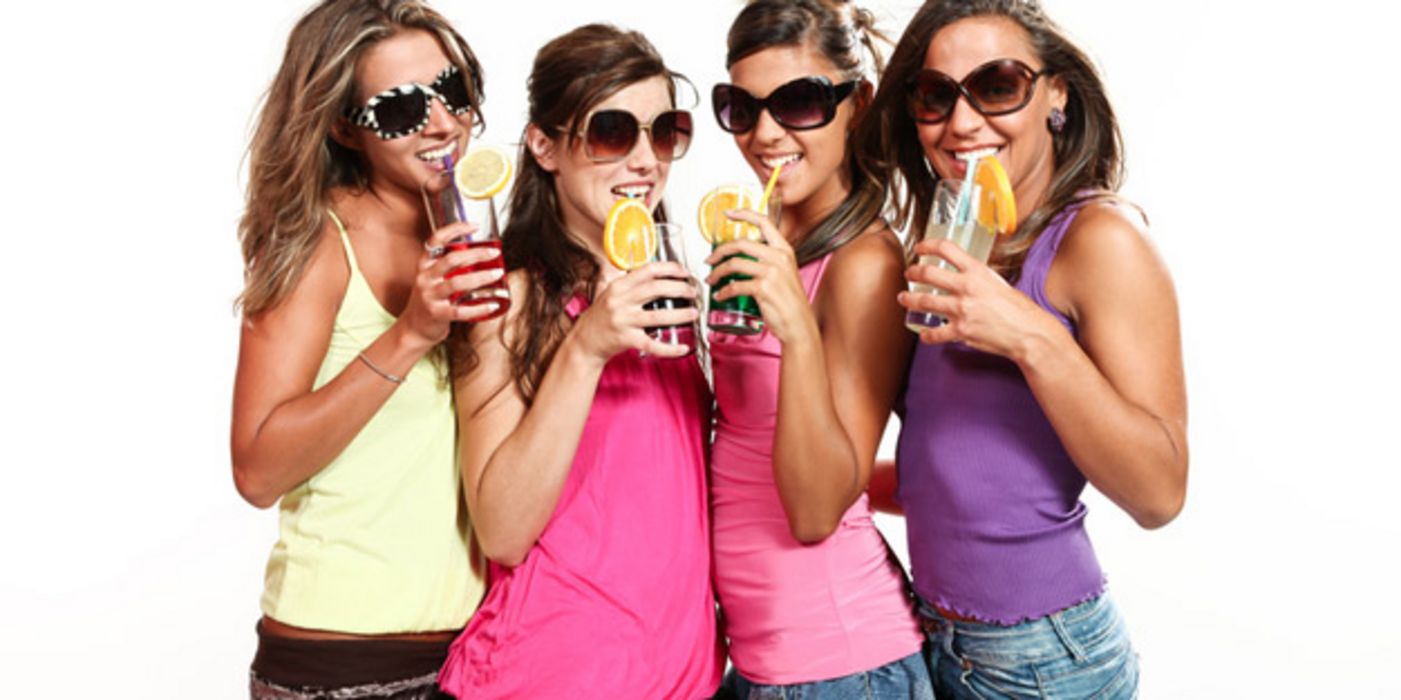 Vier Teenager-Mädchen mit Sonnenbrillen und alkoholischen Mixgetränken