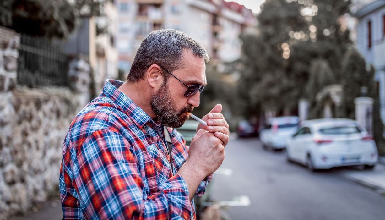 Mann, ca. 55 Jahre alt, zündet sich eine Zigarette an.