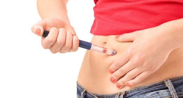 Bauchbild Jeansansatz, rotes Shirt, freier Bauch: Junge Frau spritzt sich Insulin