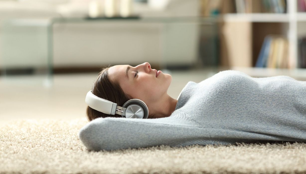 Junge Frau, liegt auf dem Boden mit Kopfhörern und entspannt.