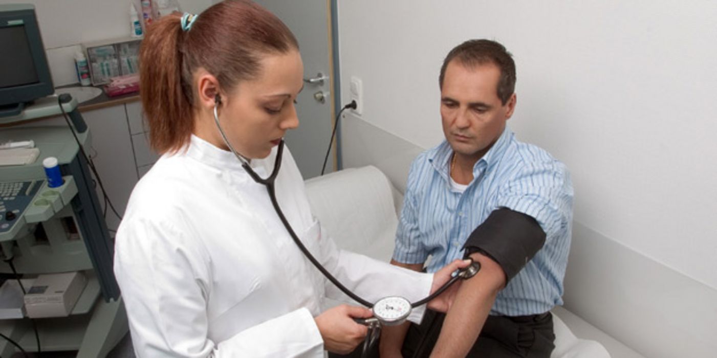 Ärztin misst Blutdruck bei Patient