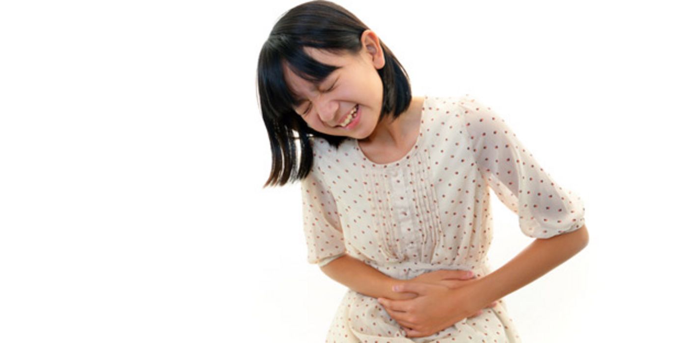 Asiatisches Mädchen, ca. 10 Jahre alt, in geblümtem Kleid, hält sich den schmerzenden Bauch