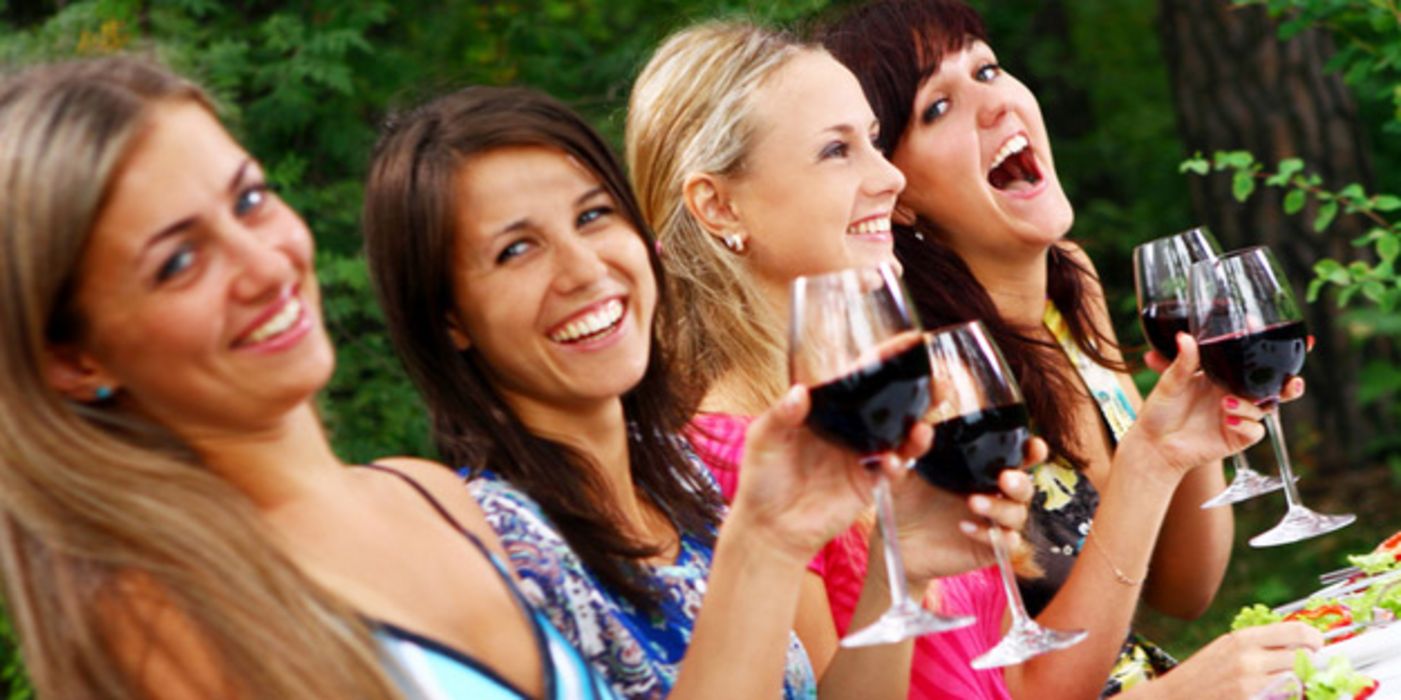 Vier junge Frauen trinken gemeinsam Rotwein.
