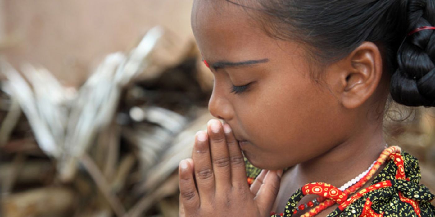 Indisches Mädchen hat die Hände zum Gebet zusammengelegt und die Augen geschlossen