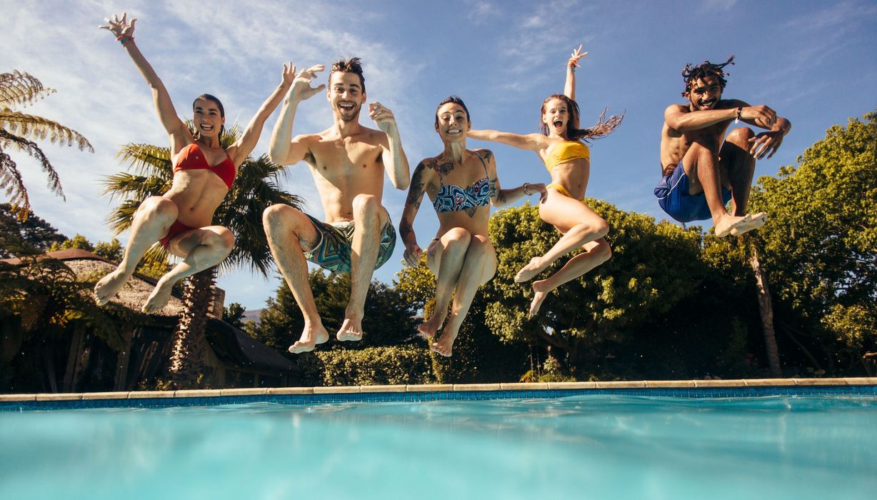 Jugendliche springen in einen Swimming Pool.
