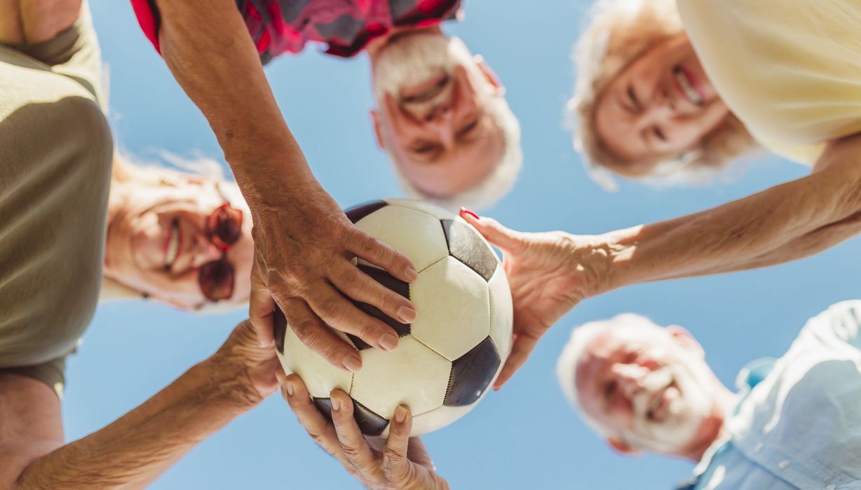 Gruppe von älteren Menschen, halten einen Fußball in der Hand.