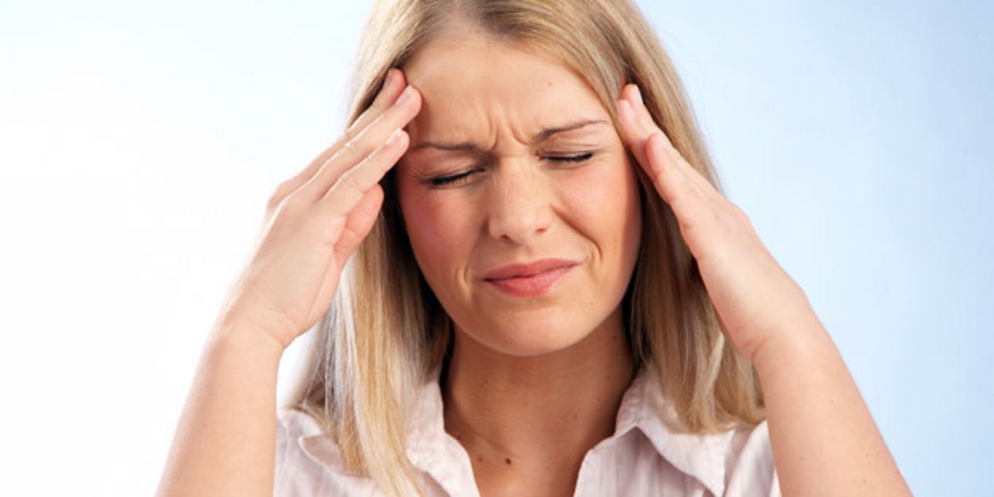 Frau mit Kopfschmerzen fasst sich an die Schläfen