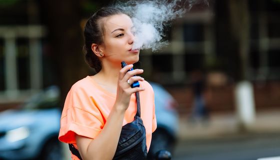Junge Frau, dampft eine E-Zigarette.