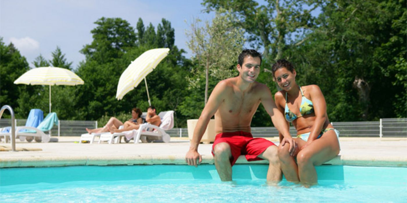 Junges Paar sitzt am rand eines Swimming-Pools.