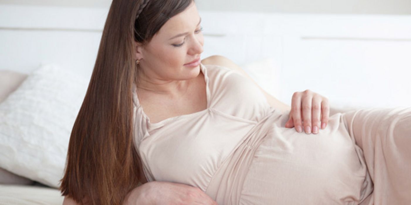 Schwangere liegt auf der Seite und betrachtet ihren Bauch