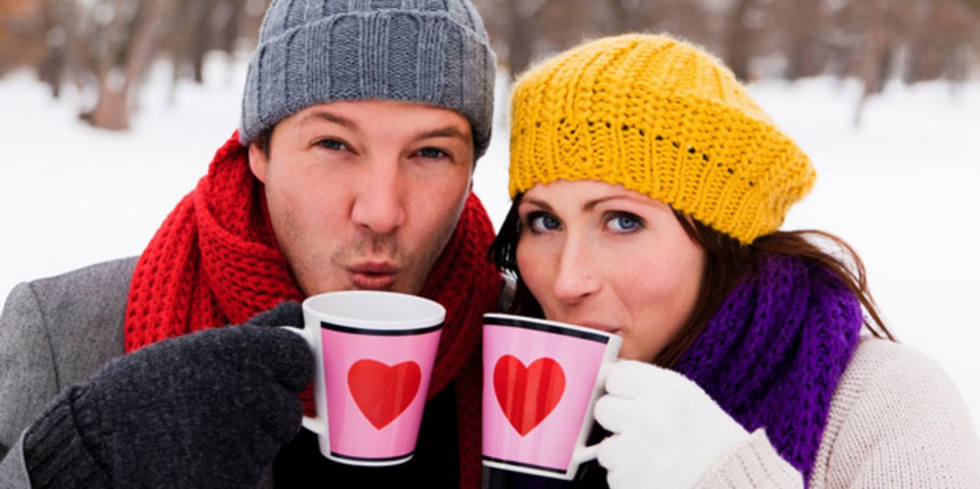Junger Mann und junge Frau mit Teetassen im Schnee