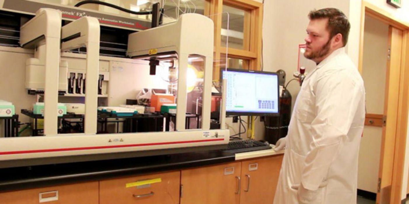 Wissenschaftler (rotbrauner Vollbart, braune Haare) im Labor vor Bildschirm