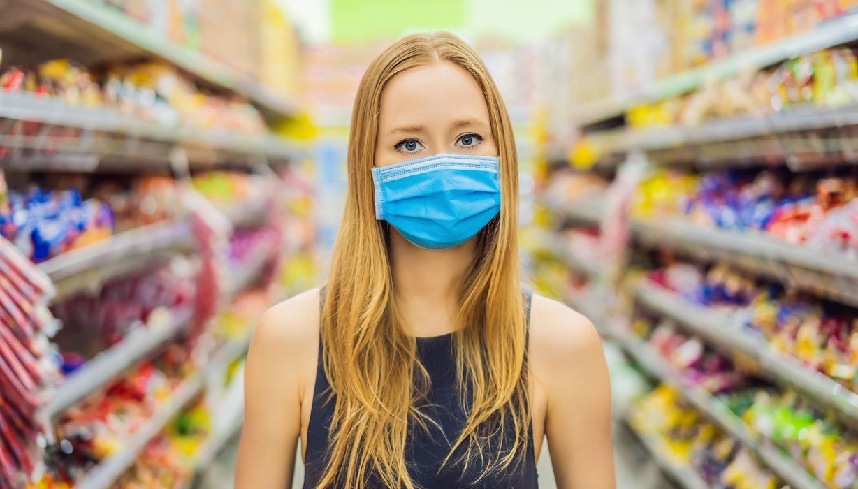 Junge Frau mit Maske im Supermarkt
