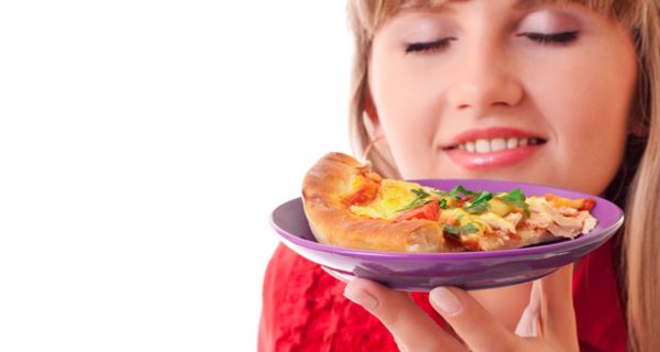 Nahaufnahme Gesicht einer jungen Frau, die an einem Stück Pizza schnuppert