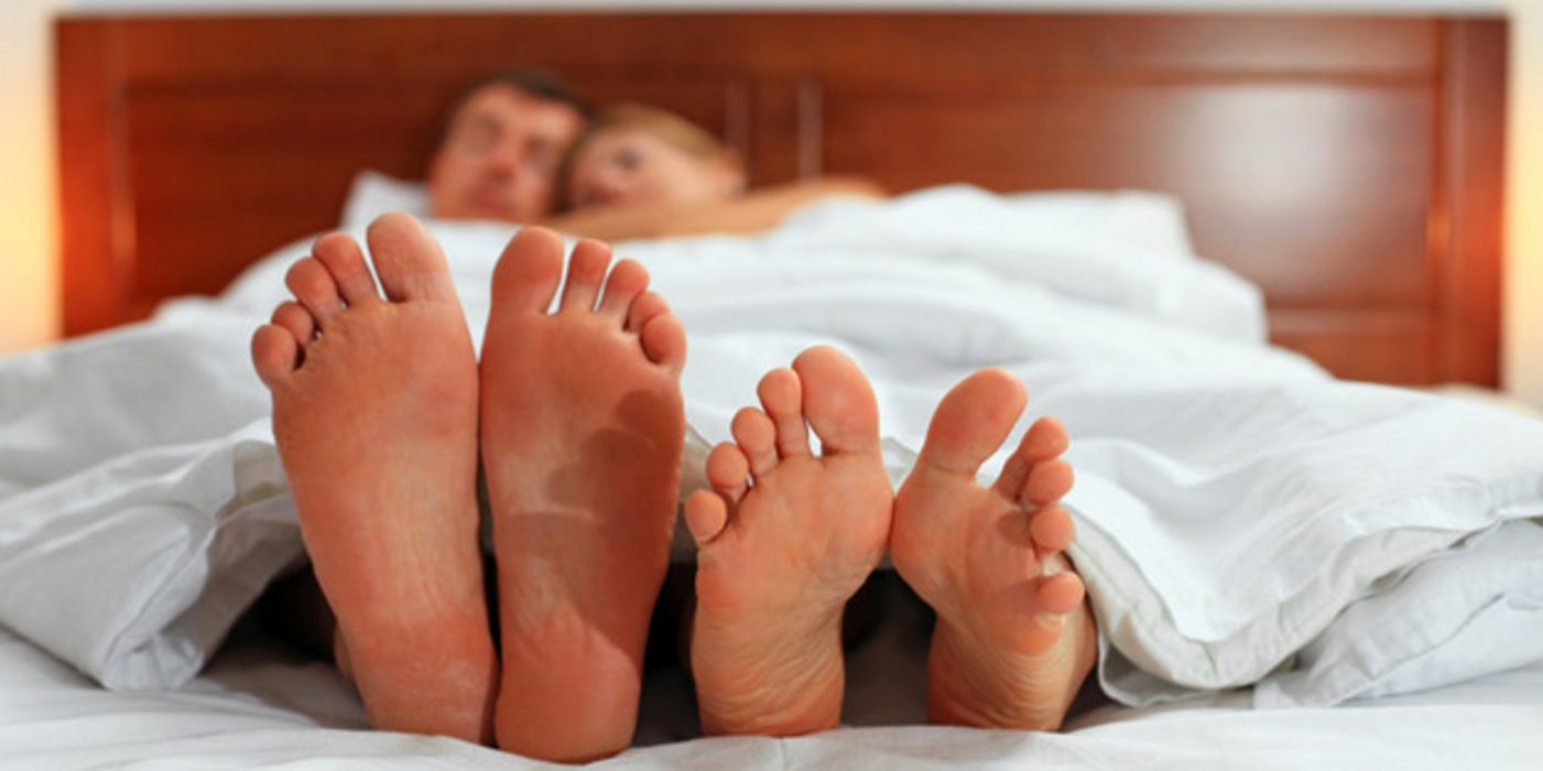 Frau und Mann im Bett schauen auf ihre nackten Füße