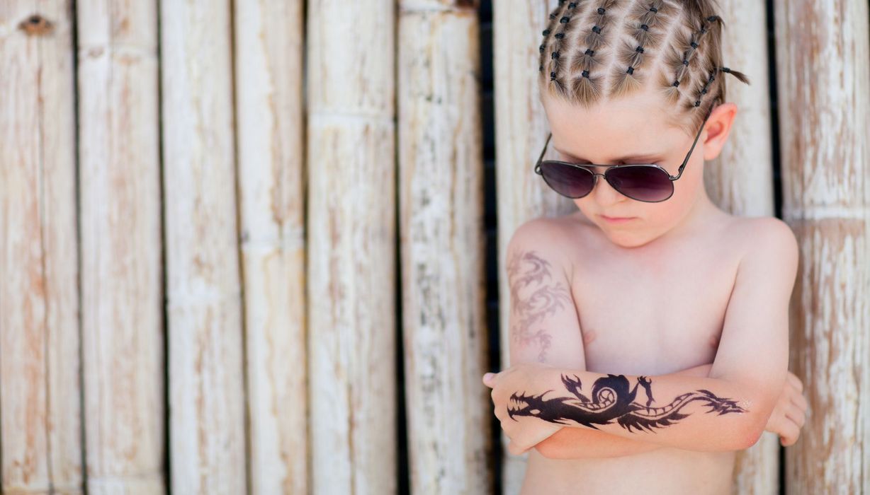 Kleiner Junge mit Sonnenbrille und Klebe-Tatto auf dem Arm.