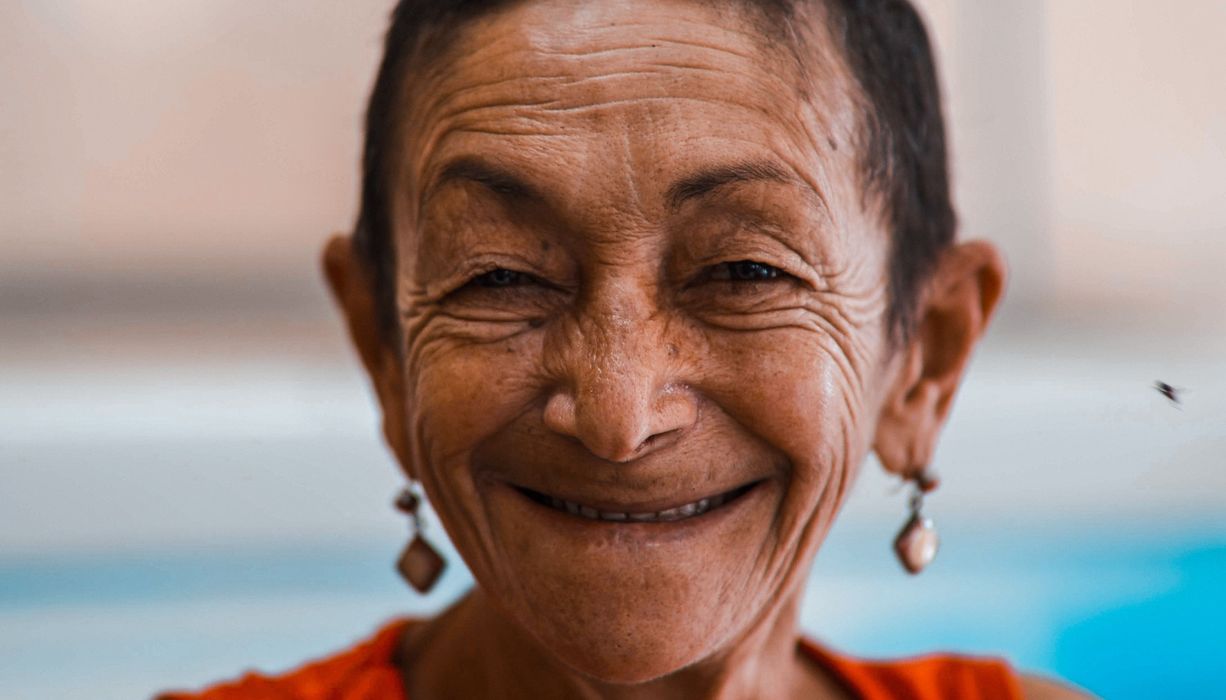 Ältere Frau, lächelt in die Kamera.