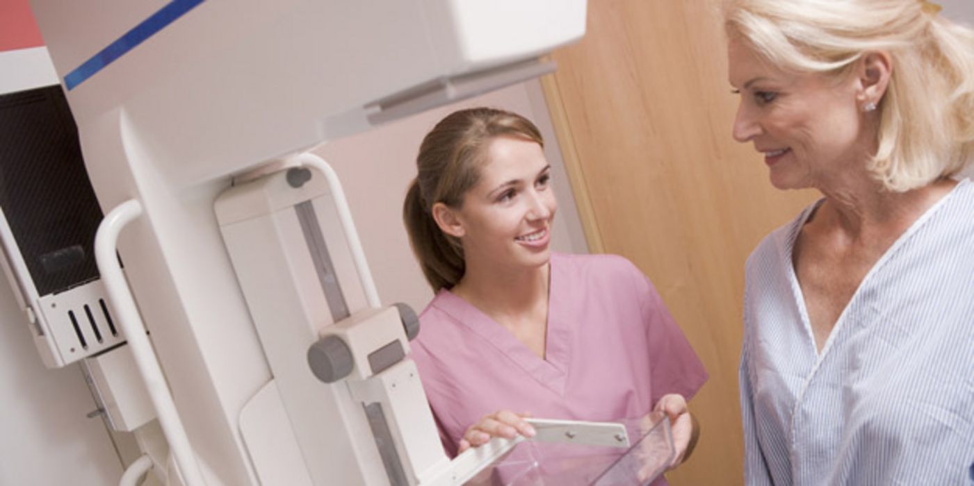 Jüngere Frau erklärt einer älteren, wie die Mammografie ablaufen wird