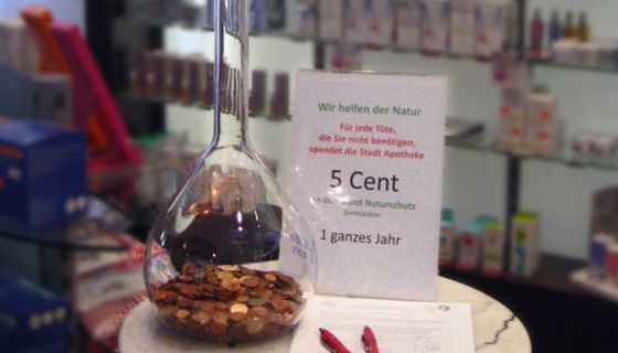 Großer Glaskolben, mit Geldstücken gefüllt auf einem kleinen Tisch in der Apotheke.