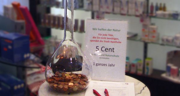 Großer Glaskolben, mit Geldstücken gefüllt auf einem kleinen Tisch in der Apotheke.