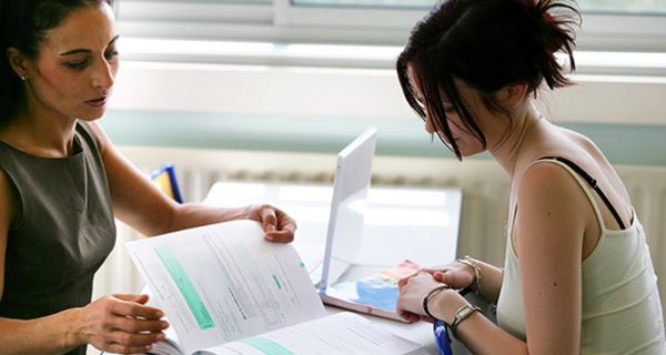 Dozentin erklärt Studentin etwas in einem Lehrbuch