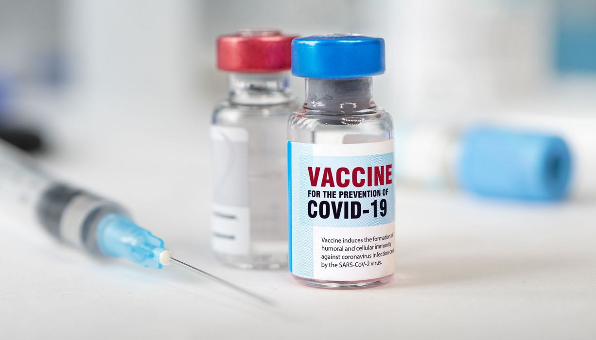 Covid-19-Impfdosen neben einer Spritze.