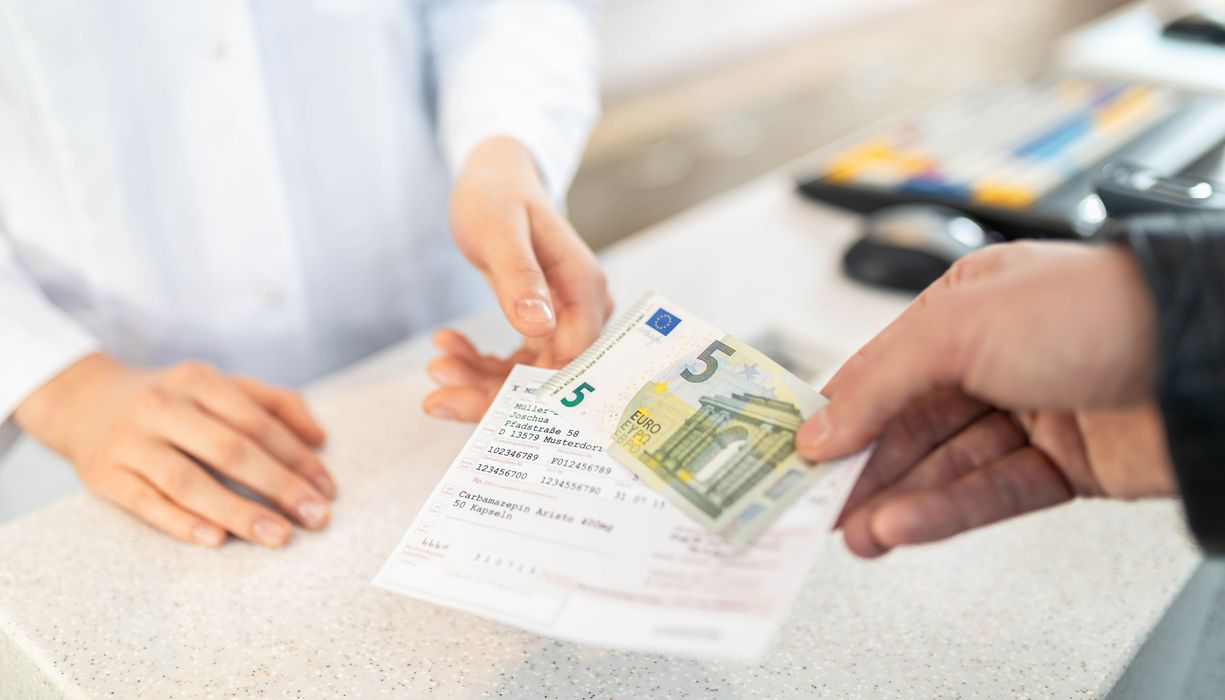Jemand reicht ein Rezept ein und gibt fünf Euro.