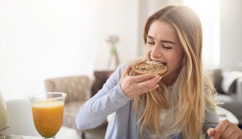 Junge Frau beißt in ein Brötchen.