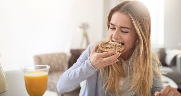 Junge Frau beißt in ein Brötchen.