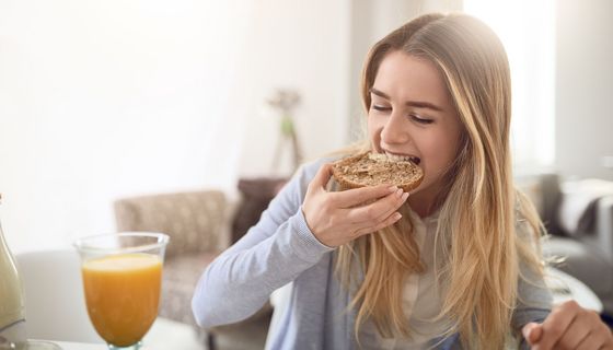 Junge Frau beißt in ein Brötchen.
