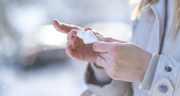 Frau cremt sich im Winter die Hände ein.