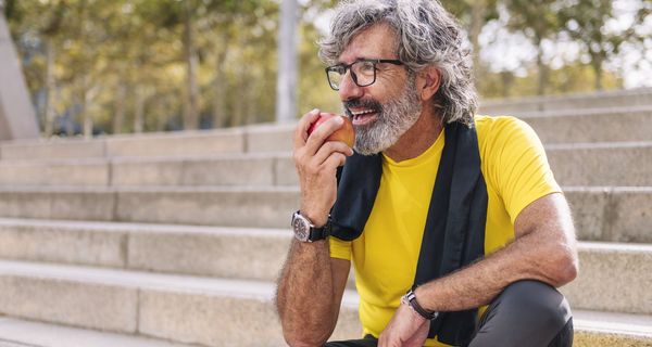 Entspannter älterer Mann beißt in einen Apfel.